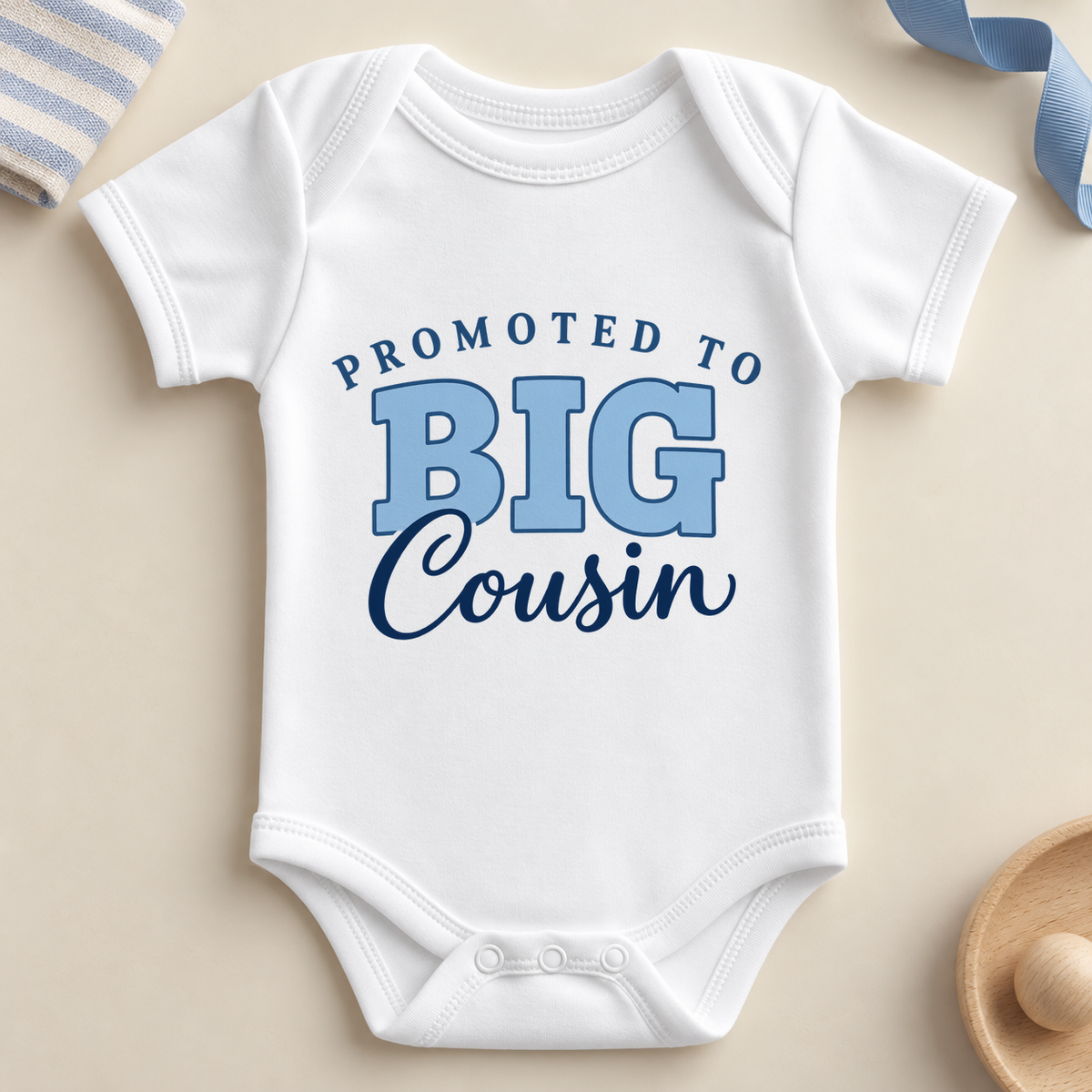 White short sleeve promoted to big cousin baby bodysuit with PROMOTED TO in arched navy letters, BIG in light blue outlined letters and Cousin in navy script